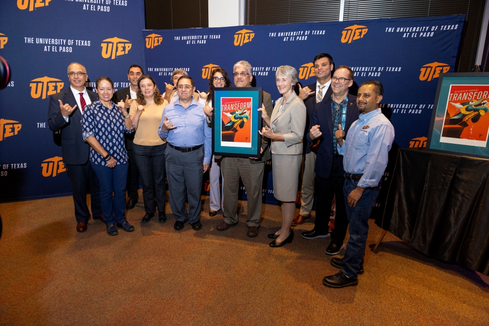 Reception attendees pose together while holding framed “Transform” artwork.